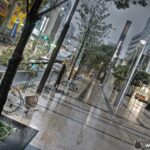 Contemporary cityscape with wet sidewalks, modern buildings, and bustling streets in urban setting.