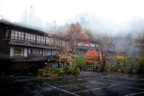 Tranquil Japanese onsen surrounded by autumn foliage, known as Awanoyu (泡の湯).