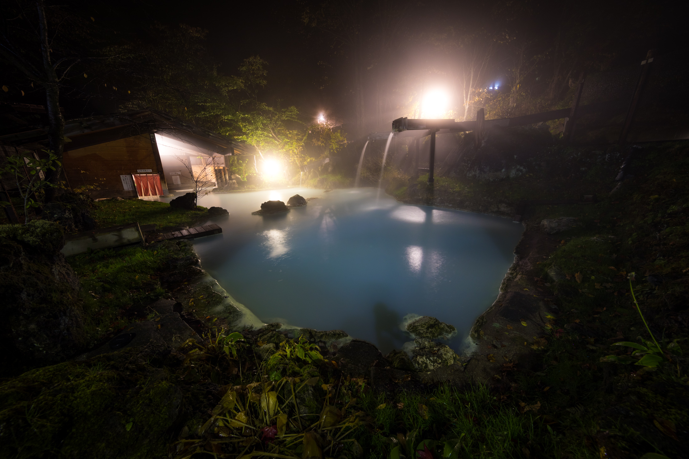Tranquil hot spring oasis with bubbling turquoise waters in a forest setting.