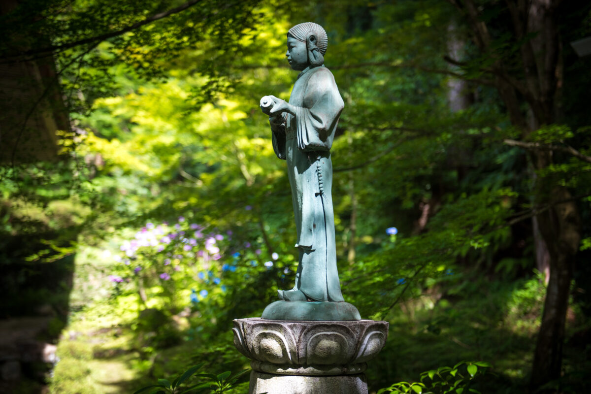 Stone Buddha statue on lotus pedestal in Kongōrin-ji Temple forest, Japan