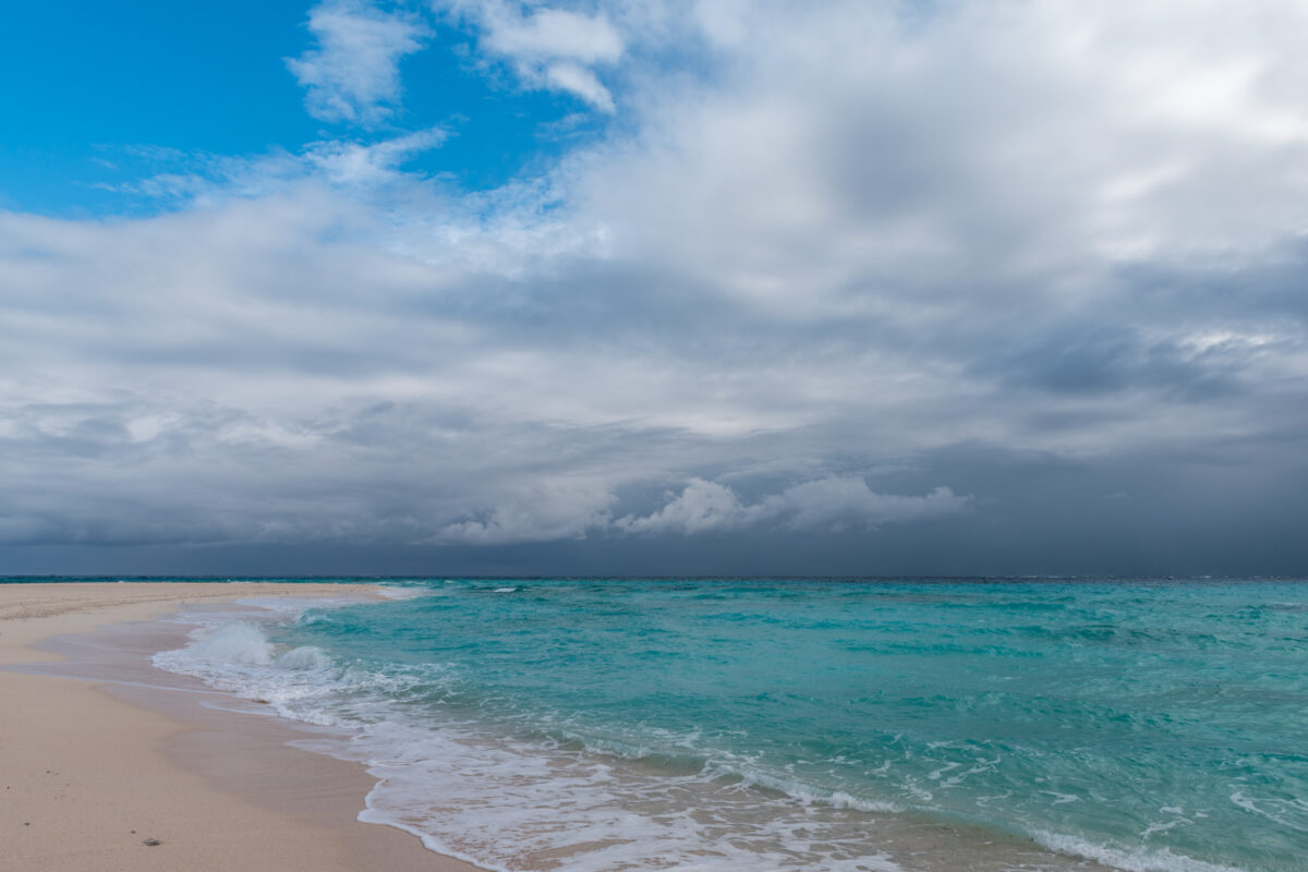 Turquoise waves on Kumejima Island beach under storm clouds in Okinawa, Japan