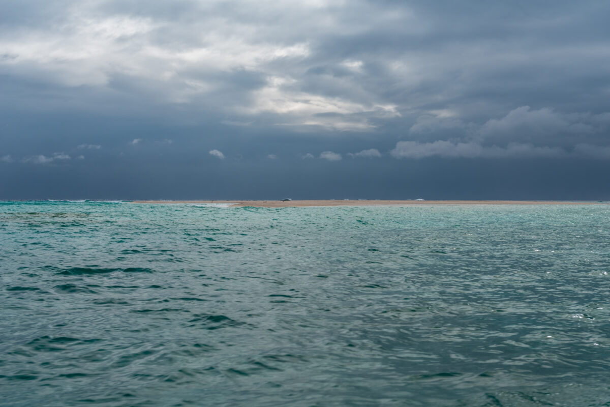 Kumejima shoreline seascape with rippled ocean water and dramatic storm clouds overhead