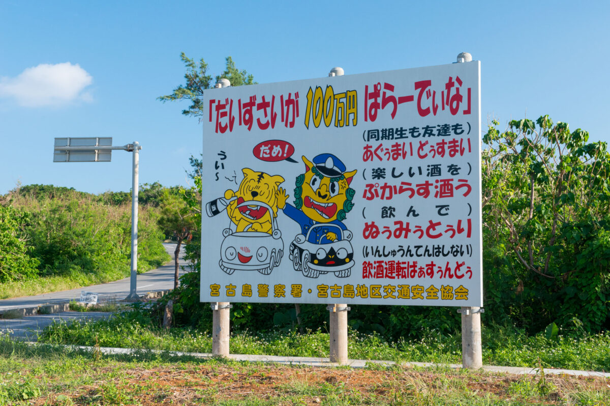 Miyako Island roadside drunk driving warning sign with cartoon driver and police officer