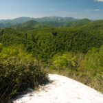 Panoramic summit view from Mount Futatsumori with forested ridges and clear blue sky