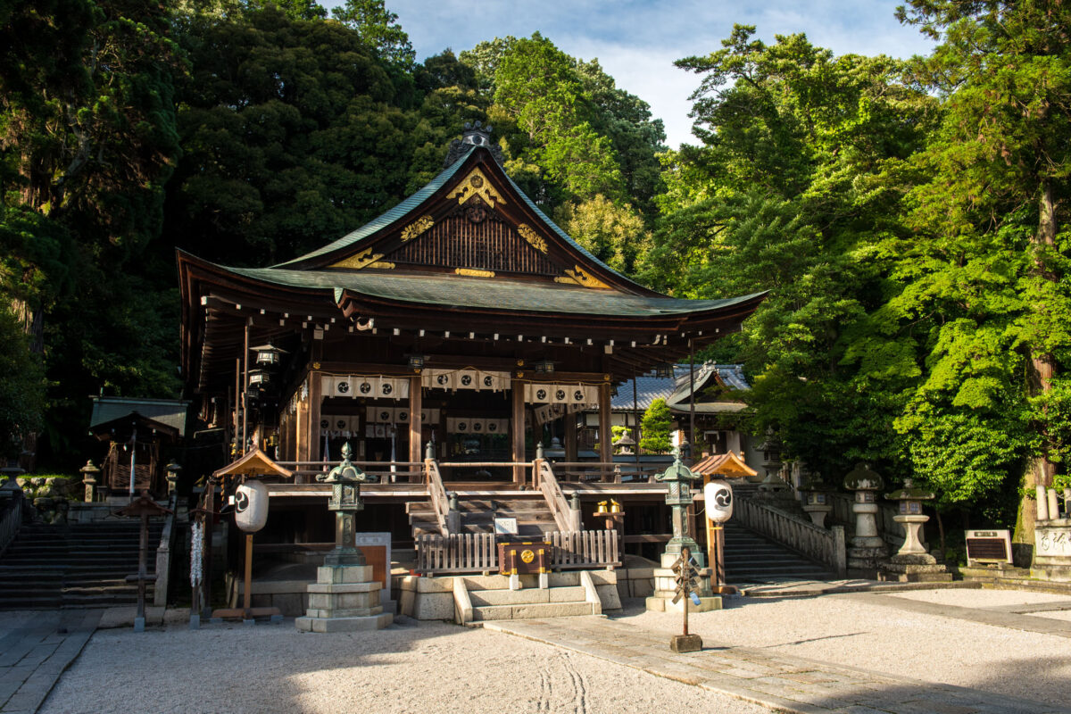 Traditional Omihachiman Shrine in Shiga, Japan, with gravel forecourt and lush trees.