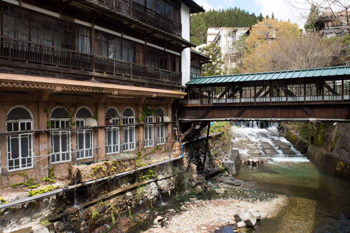 Sekizenkan Ryokan beside mountain river with green-roofed covered bridge in Japan hot spring town