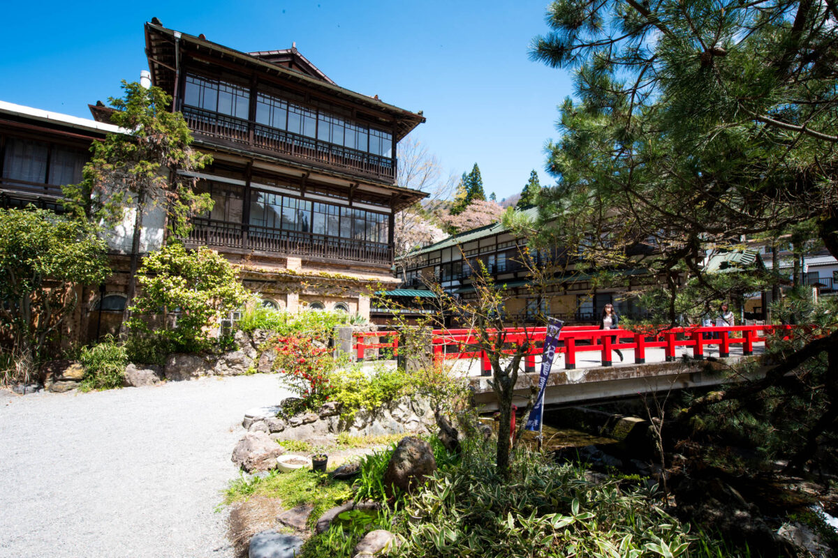 Sekizenkan Ryokan in Japan with iconic red bridge over forest stream