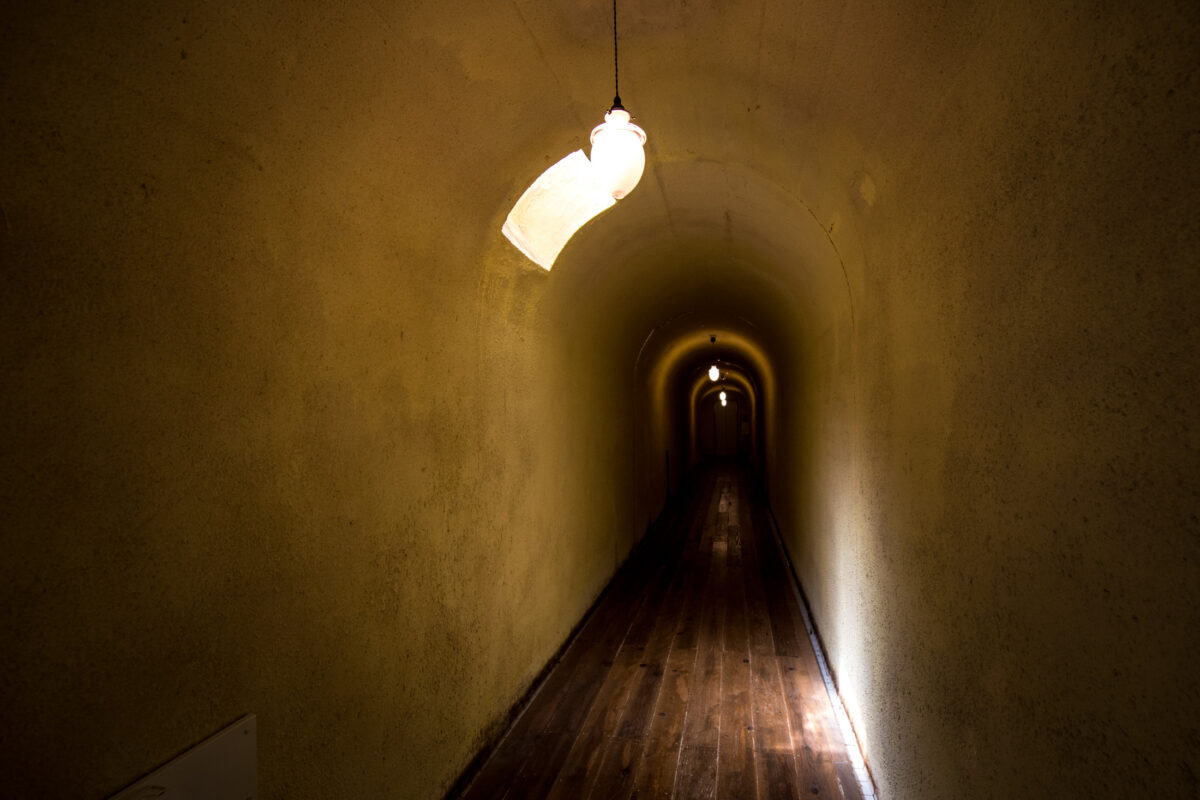 Lantern-lit tunnel corridor in Sekizenkan Ryokan with curved ceiling and wooden floor