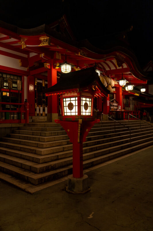 Taikodani Inari Shrine at night with vermilion buildings and glowing lantern by stone steps