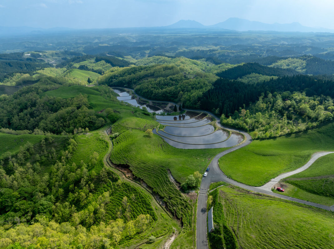 Aerial view of Ogi rice terraces in Japan, water-filled fields in a lush valley.