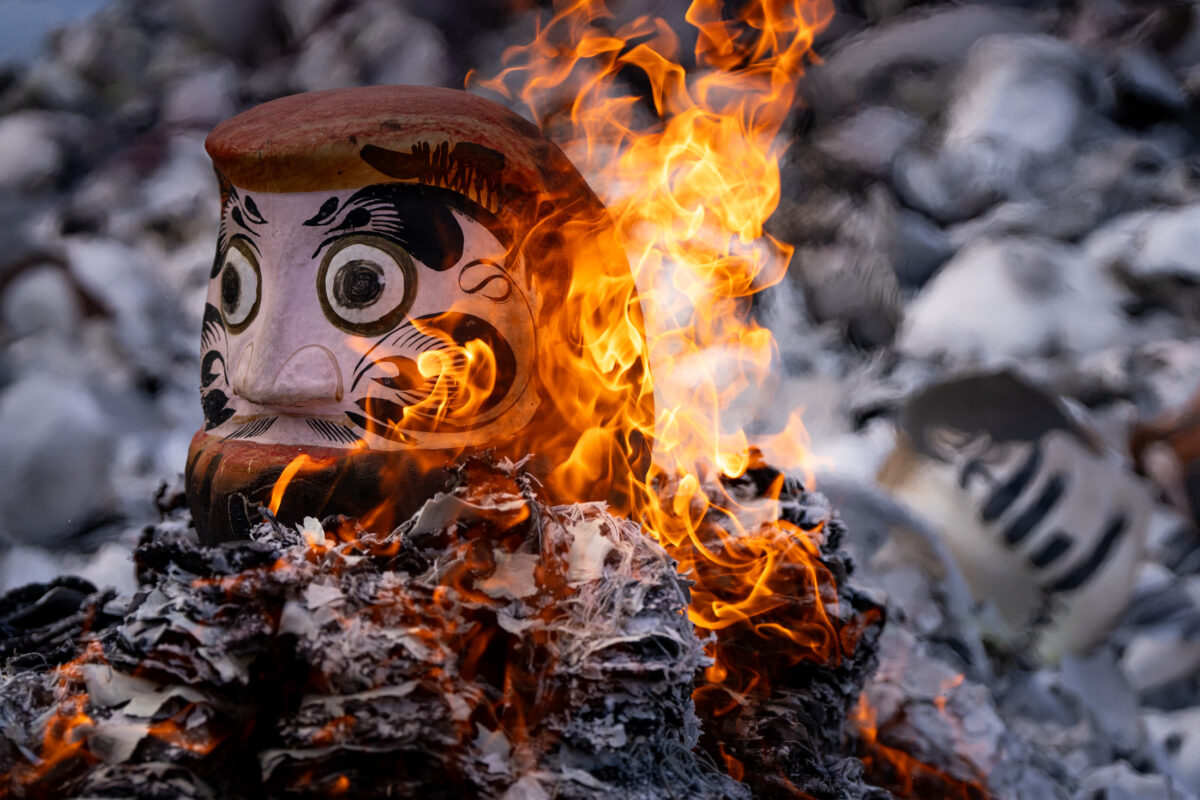 Daruma doll burning ritual at Shorinzan Temple, Japan, surrounded by flames and ash.
