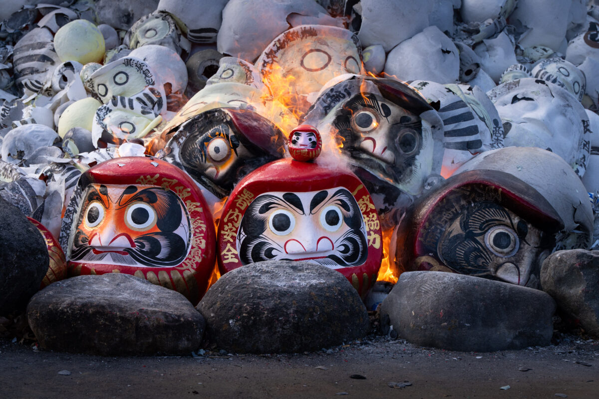 Daruma doll burning ritual at Shorinzan Temple, flames and smoke rising in winter snow.