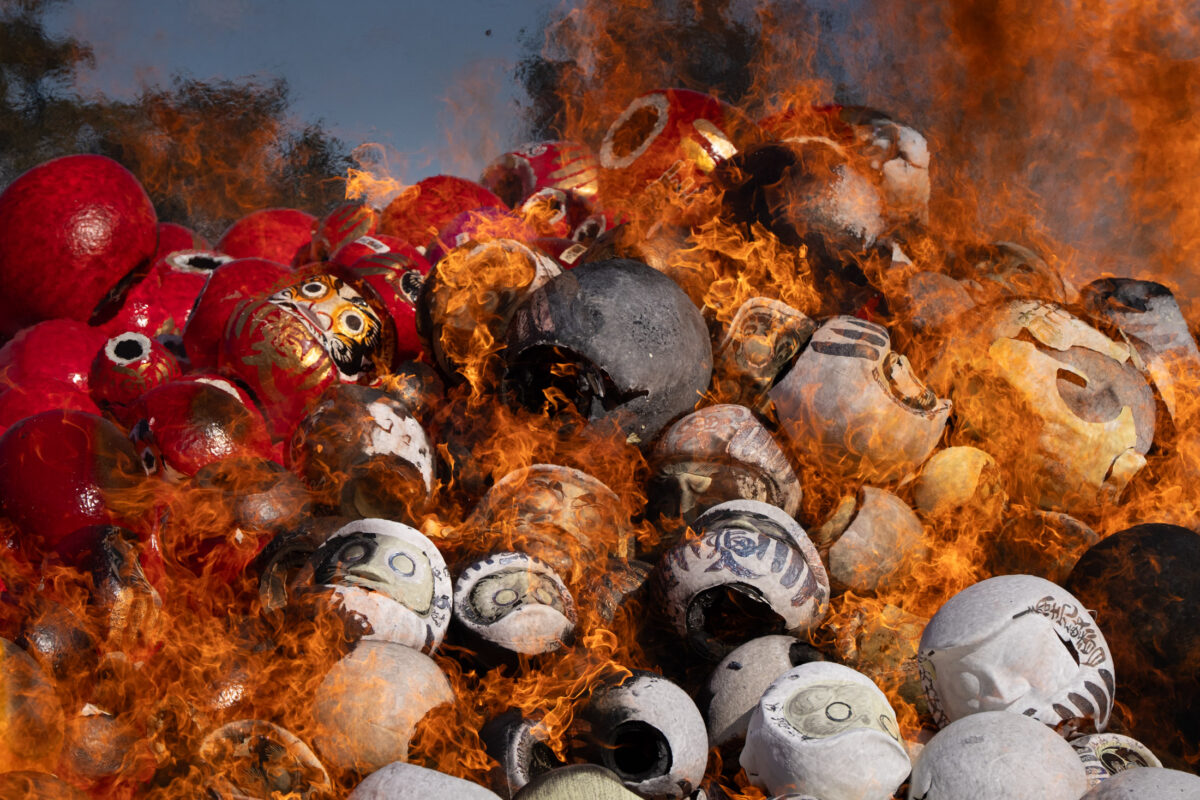 Daruma doll burning ceremony at Shorinzan Temple, Japan, with flames, smoke, and wide-eyed dolls