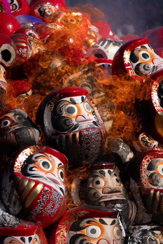 Smoke drifts through rows of Daruma dolls at Shorinzan Temple, Japan
