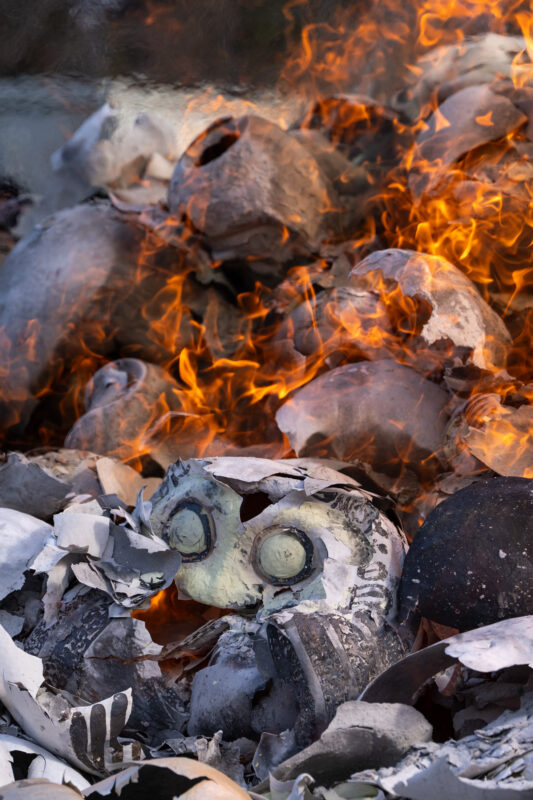 Daruma doll burning ritual flames at Shorinzan Temple, charred doll head in ash