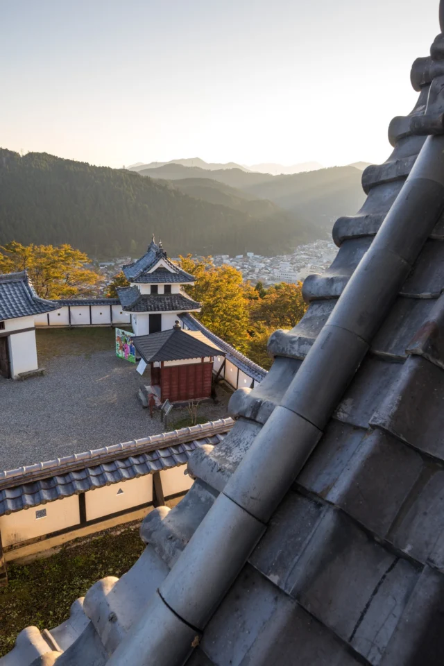 From the weathered castle roof, witness the timeless beauty of Japan as a quaint town rests peacefully amid rolling hills and a golden sky. 🌄🏯---古びた城の屋根から、静かに横たわる谷の町と黄金の空を背景に見渡す日本の時を超えた美しさ。🌄🏯---#offbeatjapan #japan #castleviews #historicjapan #sunsetmagic #explorehistory #tranquility