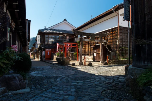 Stone roads weave stories, Under skies of endless blue, Red gate to the past.  石畳は物語を織りなす 青空の下で 過去への赤い門  #offbeatjapan #japan #edoperiod #torii #shinto #historicaljapan #architecture #traveljapan